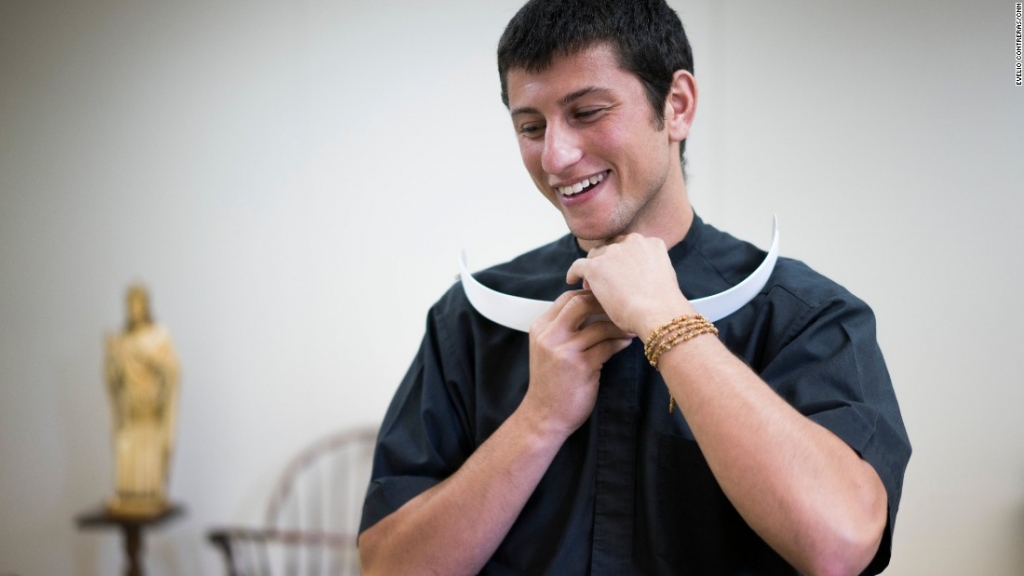 Chris Massaro a new Catholic seminarian removes his clerical collar so he can put on his vestments for Mass