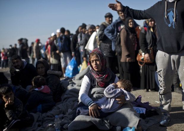 A woman holds her son as they wait in line in order to get into a reception center for migrants and refugees in Opatovac Croatia Wednesday Sept. 23