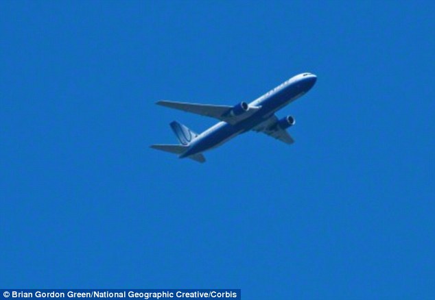 The 250-megapixel APS-H CMOS sensor can distinguish letters on the side of a flying airplane from 12 miles away. A stock image of a plane in flight is shown