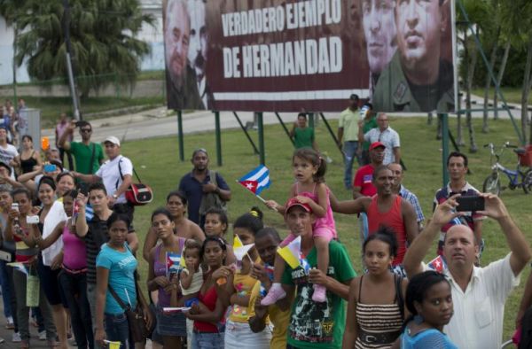 Backdropped by sign showing from left Fidel Castro