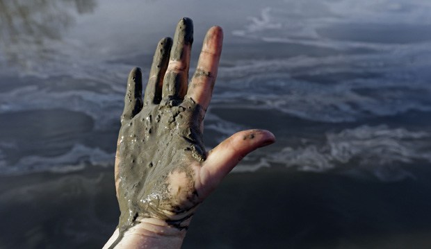 Amy Adams North Carolina campaign coordinator with Appalachian Voices shows her hand covered with wet coal ash from the Dan River swirling in the background as state and federal environmental officials continued their investigations