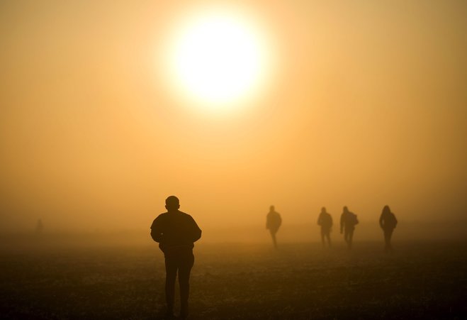 Migrants and refugees walk through a field to avoid checkpoints along the railway tracks connecting Horgos and Szeged near Roszke at the border between Hungary and Serbia Sunday Sept. 13 2015