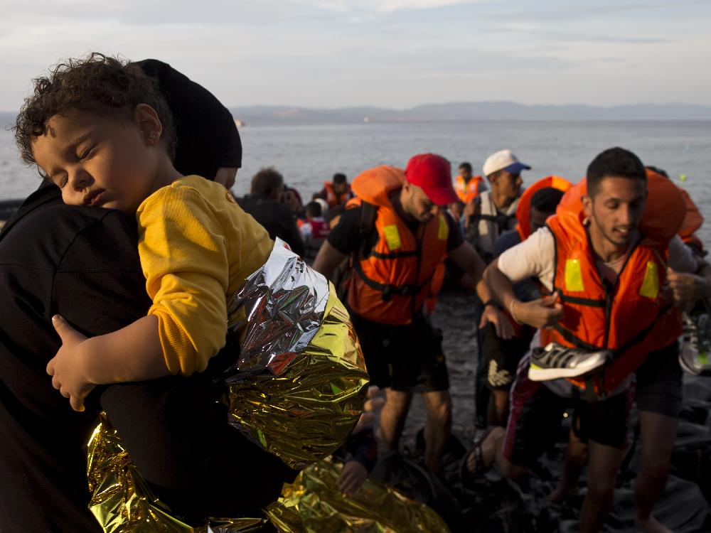 Syrian refugees arrive on a dinghy after crossing from Turkey to Lesbos island Greece Wednesday Sept. 9 2015. The head of the European Union's executive says 22 of the member states should be forced to accept another 120,000 people in need of int