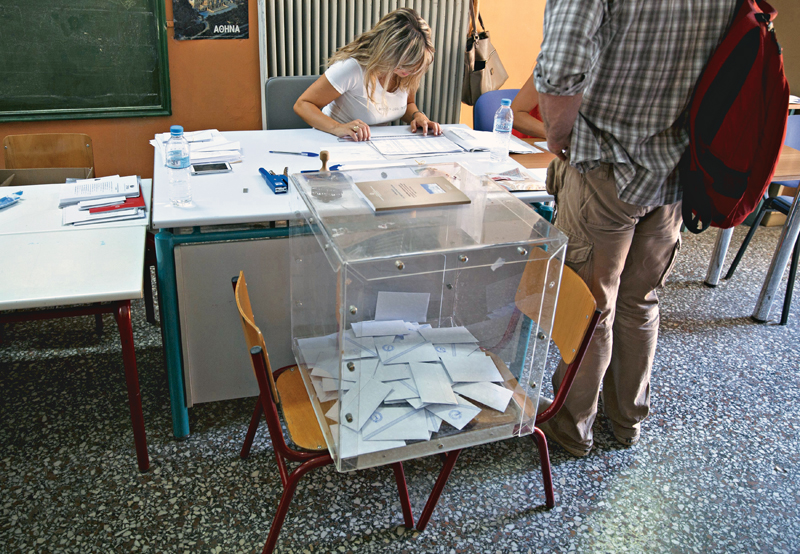 REFILE – ADDING DROPPED WORD IN FIRST SENTENCE A nearly empty ballot box is seen at a polling station as an official checks the identification of a voter during a general election in Athens Greece