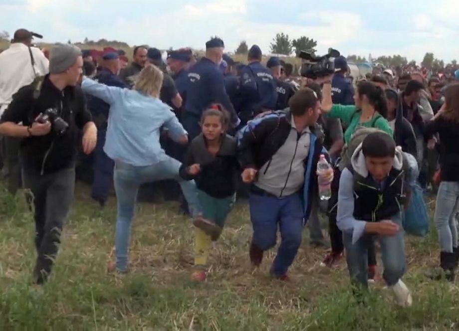 In this image taken from TV a Hungarian camerawoman center left in blue kicks out at a young migrant who had just crossed the border from Serbia near Roszke Hungary Tuesday Sept. 8 2015. The camerawoman has been fired after she was caught on video kic