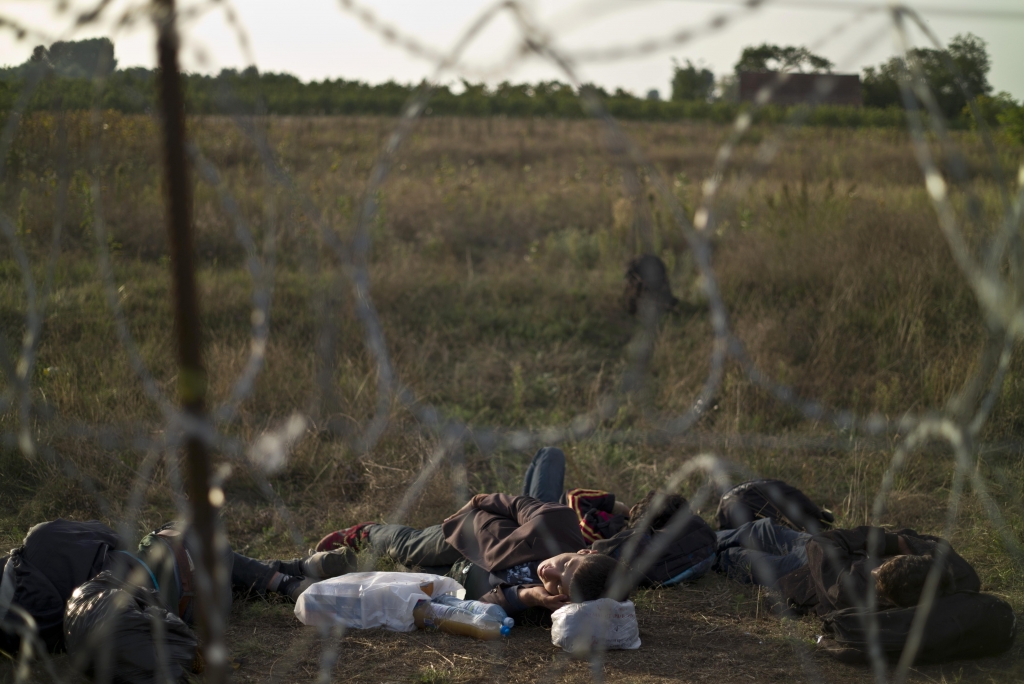 Afghan refugees sleep next to razor-wire barrier at the Serbian side of Hungary's border fence with Serbia in Asotthalom southern Hungary Sept. 17 2015