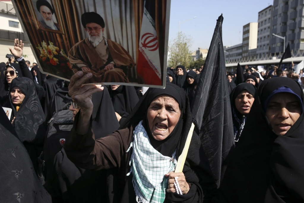 An Iranian worshipper holds a poster of Iranian Supreme Leader Ayatollah Ali Khamenei and late revolutionary founder Ayatollah Khomeini at top left of the poster as she chant slogans while attending an anti Saudi protest rally on Thursday after their F