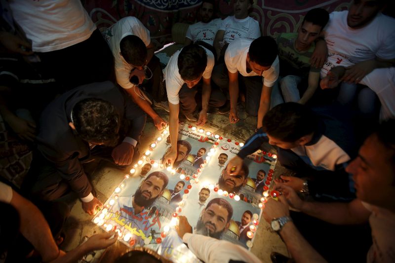 Palestinians light candles on posters depicting Palestinian detainee Mohammed Allan during a protest in support of Allan in the West Bank city of Hebron. – Reuters pic