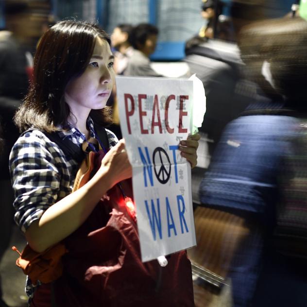 A young woman holds a placard protesting against controversial military reform bills outside Japan's parliament in Tokyo Japan on Friday. Lawmakers passed two measures to expand the role of Japan's military for the first time since World War I