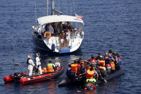 A Frontex zodiac approaches a dinghy with Syrian refugees onboard that was tugged by a United States flagged sailing boat near the shores of the Greek island of Lesbos