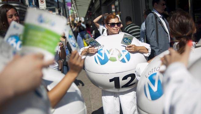 Janine Lubey centre promotes the Lotto Max lottery at Yonge and Dundas Square in Toronto on Friday