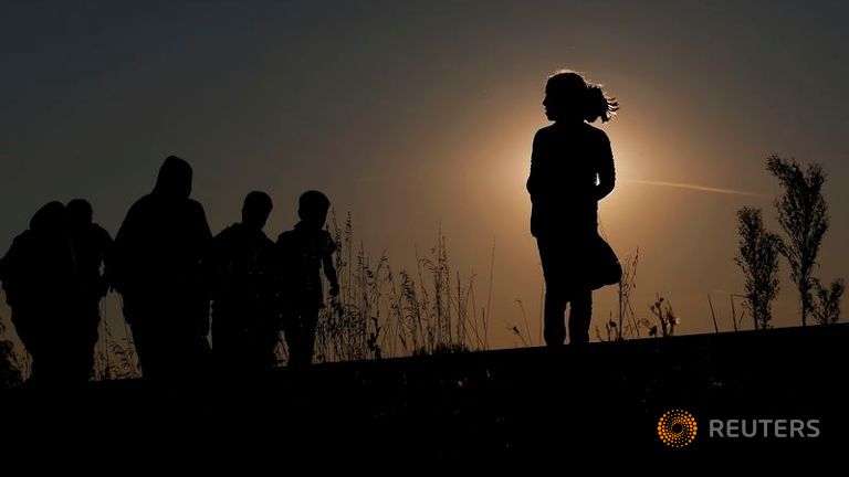 Migrants walk along rail tracks on sunset close to a migrant collection point in Roszke Hungary