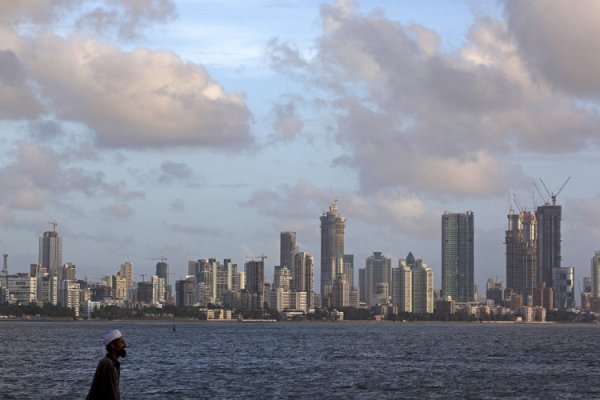 A man walks at the seafront as scattered clouds are seen over Mumbai's skyline India