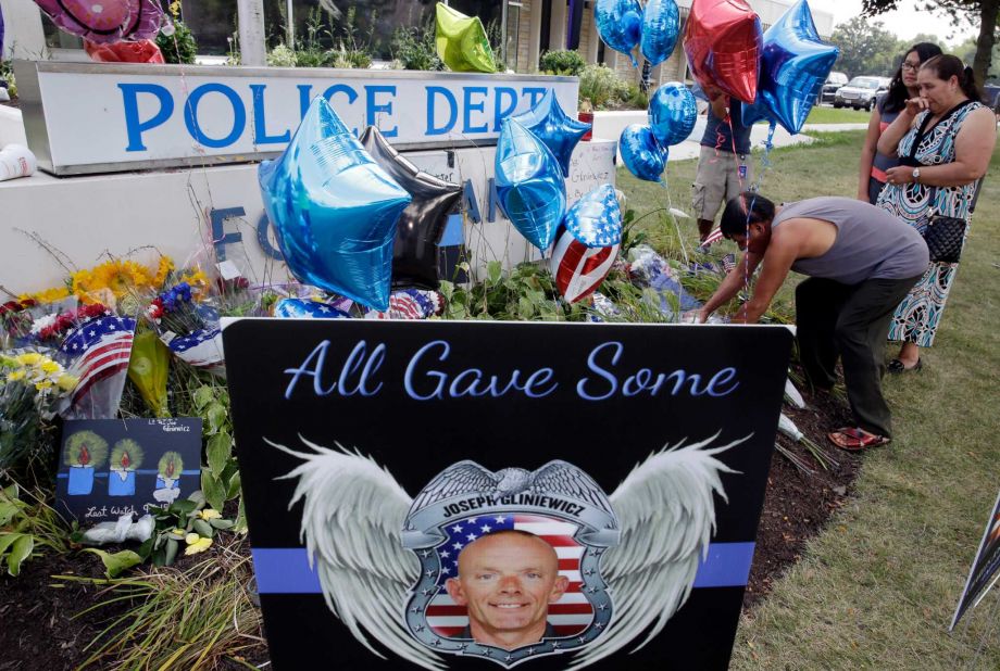 People pay respects to Lt. Joe Gliniewicz at a makeshift memorial outside the Fox Lake Police department on Wednesday Sept. 2 2015 in Fox Lake Ill. Fox Lake Police Lt. Charles Joseph Gliniewicz was shot and killed Tuesday while pursuing a group of sus