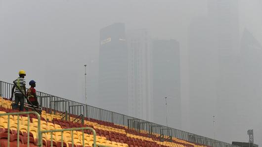 Workers install spectators seats for the Formula One street circuit as financial district buildings are shrouded with haze in Singapore