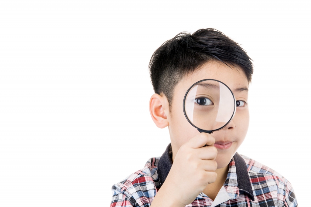 Myopia little boy looks through magnifying glass