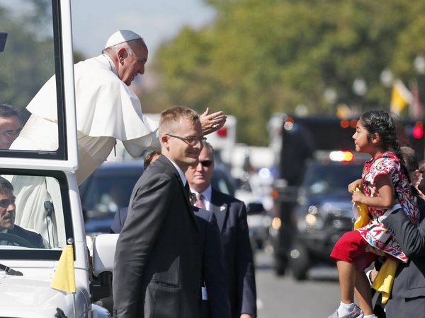 Pope Francis reaches for a child from the popemobile that was brought to him during a parade in Washington Wednesday Sept. 23 2015