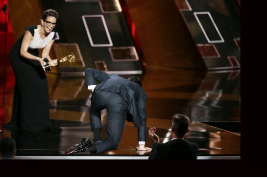 Tina Fey reacts as Jon Hamm climbs on stage for his award during the 67th Annual Primetime Emmy Awards