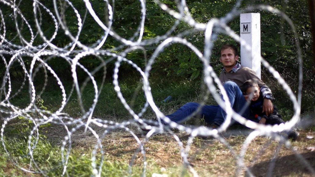 A young man and his son lean on a border stone after he was stopped by Hungarian soldiers at the border exit between Serbia and Hungary in Asotthalom near Roszke southern Hungary Tuesday