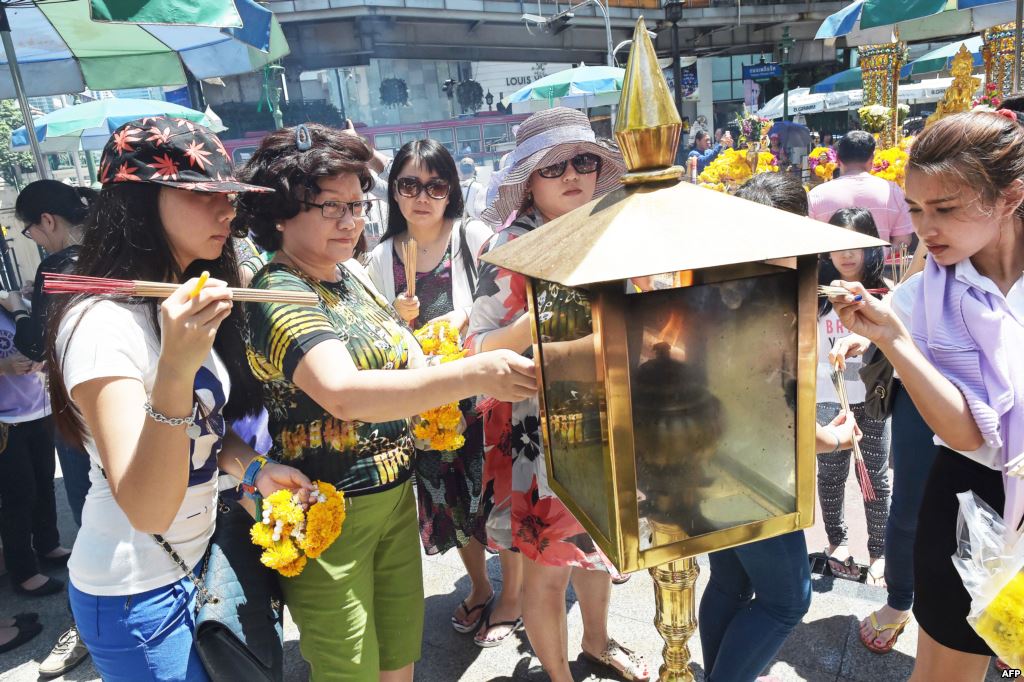 FILE- Women light incense sticks before offering prayers at the reopened Erawan Shrine the popular tourist site where 20 people were killed on August 17 in a bomb blast in Bangkok Aug. 20 2015