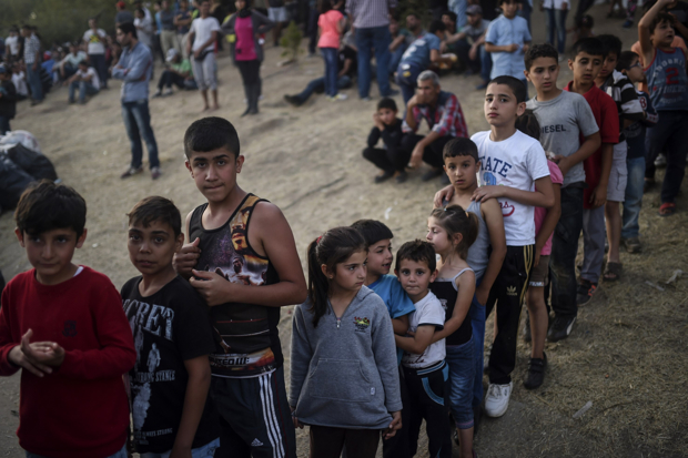 Syrian refugees queue for food as they rest beside the highway on their way to the border between Turkey and Greece