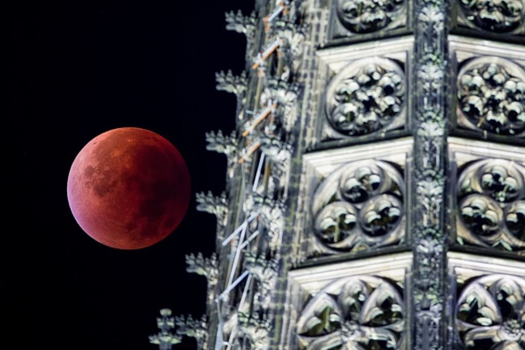 The super blood moon can be seen behind one of the steeples of the Cologne Cathedral in Cologne western Germany