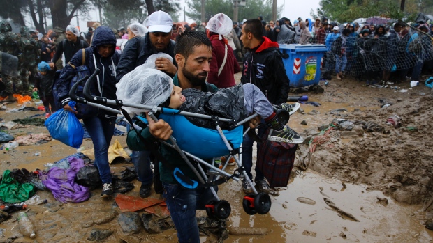 A man carries a child through thick mud as they cross the border from Greece into Macedonia near the Greek village of Idomeni