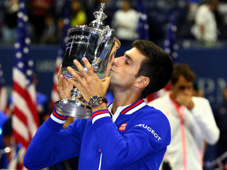 Novak Djokovic celebrates with the trophy after defeating Roger Federer
