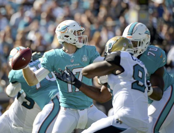 Miami Dolphins quarterback Ryan Tannehill throws a pass as he is pressured by Jacksonville Jaguars defensive end Chris Clemons left during the first half of an NFL football game in Jacksonville Fla