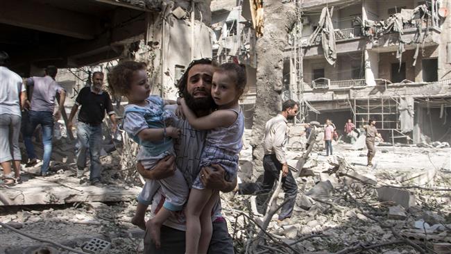 A Syrian man carries his two daughters as he walks across the rubble in the militant-held neighborhood of al Kalasa in the northern Syrian city of Aleppo