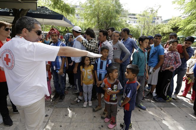 Red Cross volunteers distribute sandwiches and water to Afghan migrants at Victoria square in Athens Tuesday Sept. 8 2015 where many migrants stay temporarily before continuing their trip to more prosperous European countries. Frontex the EU border