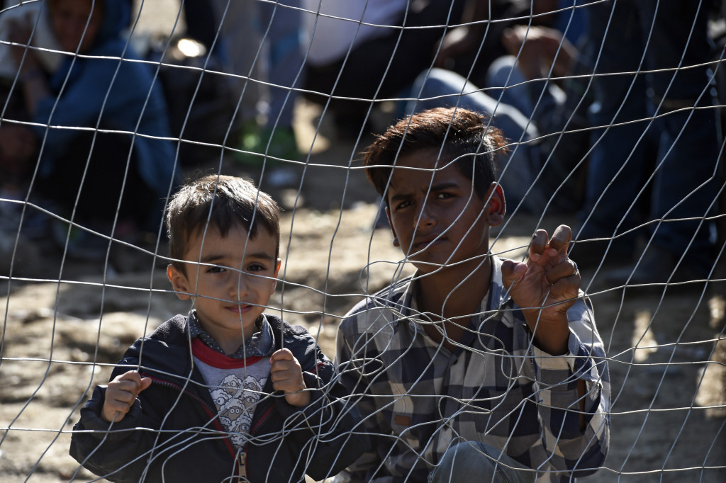 Migrant children look through a fence as they wait permission to cross the border between Greece and Macedonia Sept. 15.'Do not abandon victims of conflicts in Syria and Iraq Pope Francis said