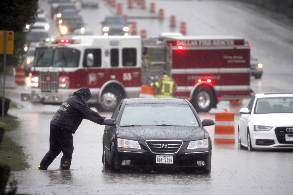 A Dalls Fire Rescue responder makes his way over to a stalled vehicle to check on the driver still inside on Friday in Dallas