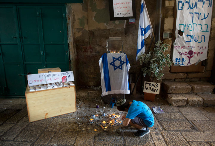 A Jewish boy lights candles where a stabbing attack took place in Jerusalem's Old City- AP