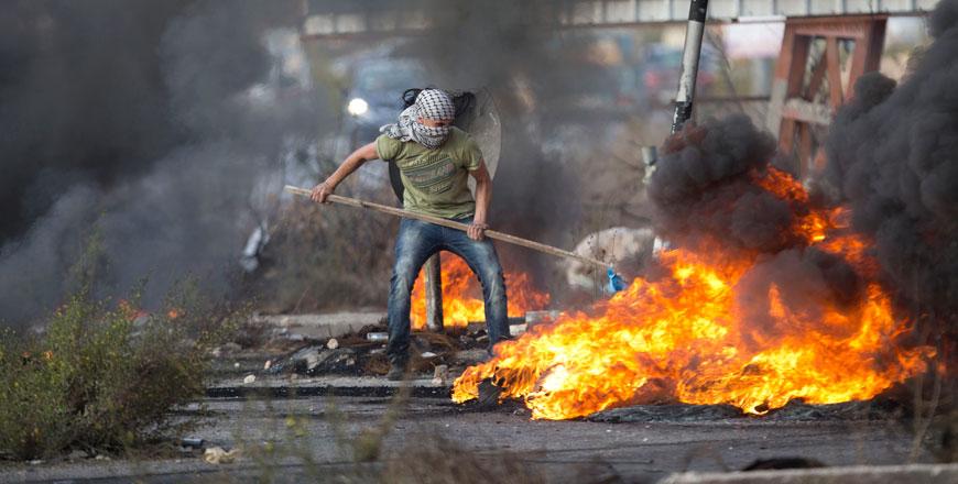 A Palestinian pushes burning tyres during clashes with Israeli troops near Ramallah West Bank Tuesday