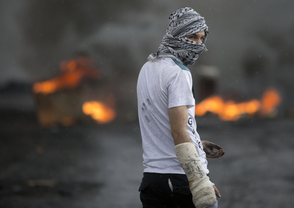 A Palestinian stands amid smoke from burning tires during clashes with Israeli troops near Ramallah on Thursday