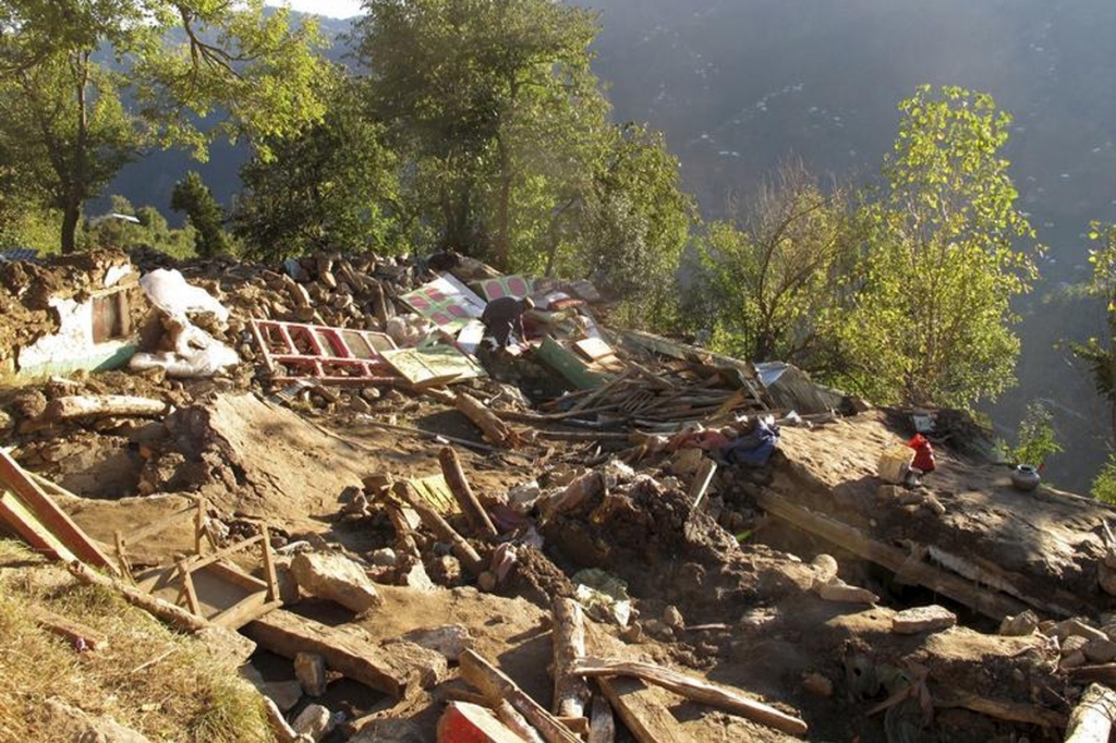 A man sorts through his belongings at the site of his house which was damaged by the earthquake