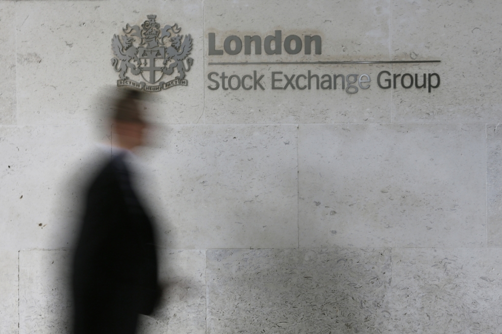 A man walks past the London Stock Exchange in the City of Lond