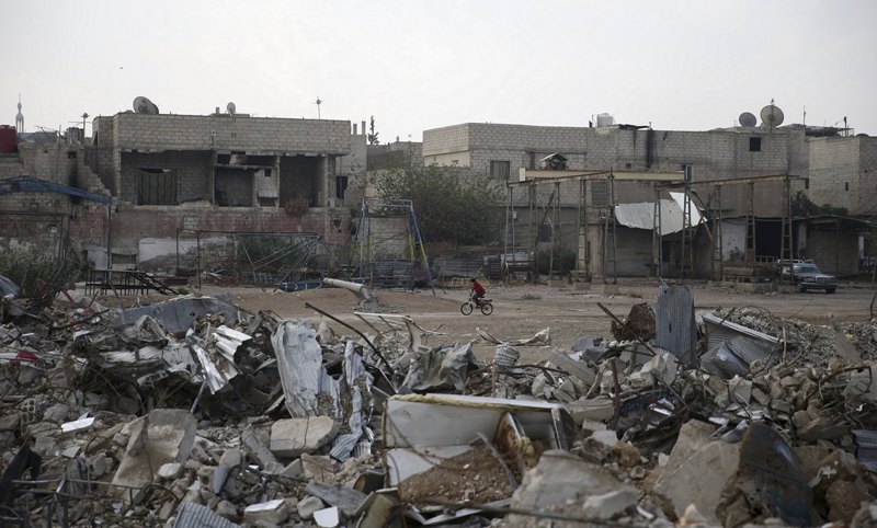 A resident rides a bicycle near damaged buildings in the town of Douma eastern Ghouta in Damascus Syria