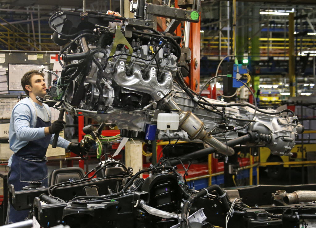 A worker at the GM Arlington plant installs an engine in an SUV