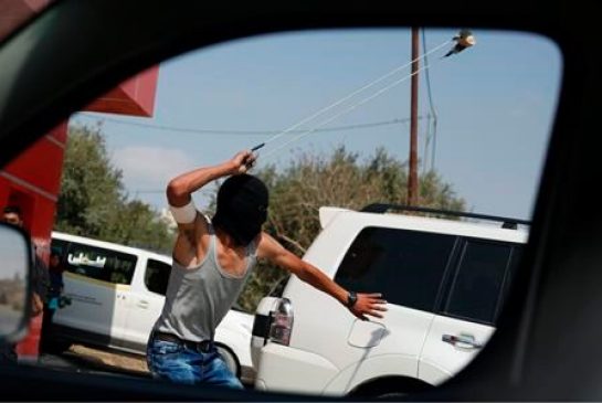 A Palestinian uses a slingshot during clashes following a demonstration in the West Bank city of Ramallah Monday Oct. 5 2015