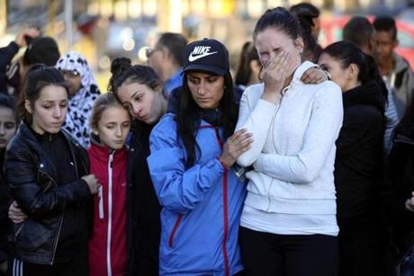 People stand outside Kronan school after Thursday's attack in Trollhattan Sweden Friday Oct. 23 2015. It was a racially motivated carefully planned rampage police say. The 21-year-old masked man marched through a Swedish school with a sword