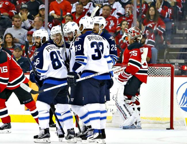 Jets’ Andrew Ladd center getting congratulated by teammates after scoring a second-period goal against Devils