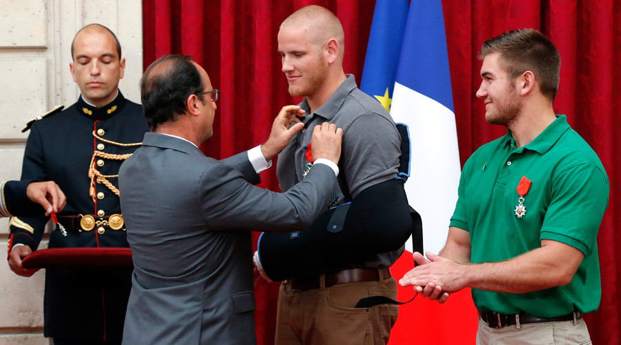 French President Francois Hollande awards U.S. Airman First Class Spencer Stone with the Legion d'Honneur medal as U.S. National Guardsman Alek Skarlatos applauds during a ceremony at the Elysee Palace in Paris France