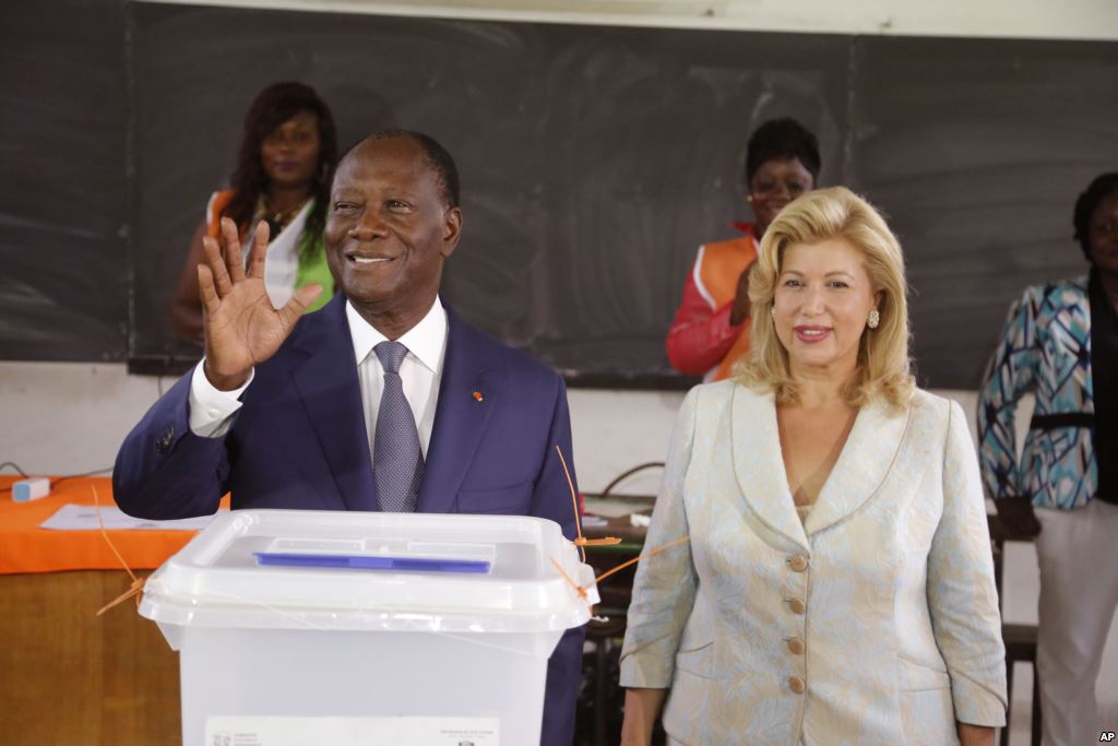 FILE- Ivory Coast’s president Alassane Ouattara left waves after casting his ballot with his wife Dominique Ouattara right at a polling station during elections in Abidjan Ivory Coast Sunday Oct. 25 2015