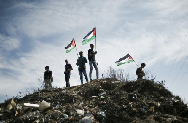 Palestinian demonstrators wave their national flag during an anti Israel protest east of Khan Yunis in the southern Gaza Strip near a border fence with Isr