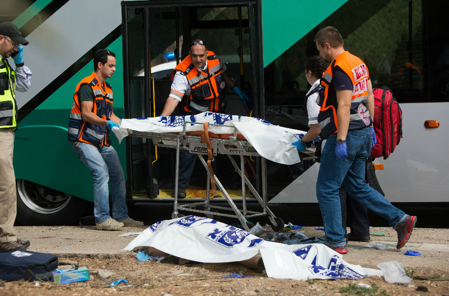 Rescue personnel working near a victim of a terror attack in the East Talpiot neighborhood of Jerusalem in which two people were killed and more than a dozen wounded on a city bus by two assailants armed with a gun and a knife