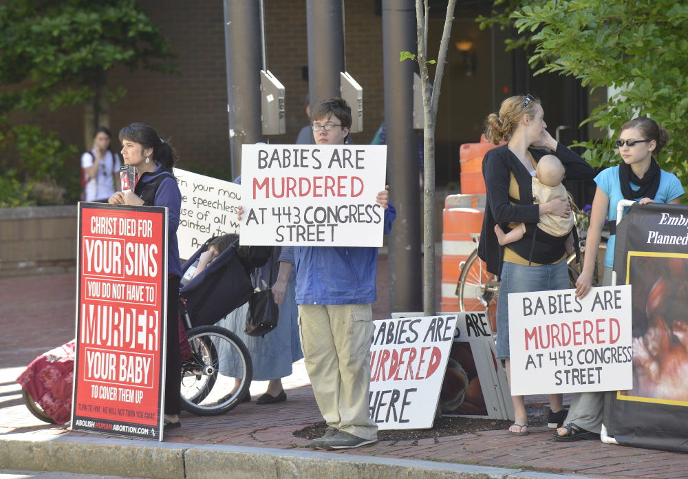 Anti-abortion activists stand across Congress Street from the Planned Parenthood of New England's clinic. AP