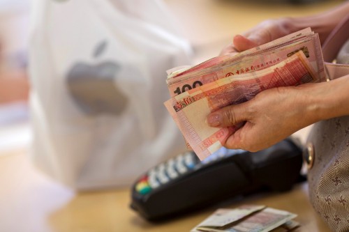 A customer holds a bundle of Hong Kong dollar banknotes while purchasing an Apple Inc. iPhone 6 at the company's Causeway Bay store during the sales launch of the iPhone 6 and iPhone 6 Plus in Hong Kong China on Friday Sept. 19 2014. Apple stores