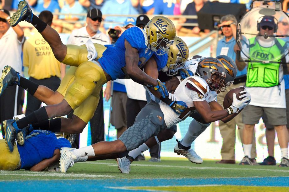 Arizona State wide receiver Tim White second from right scores a touchdown under pressure from UCLA defensive back Tahaan Goodman left and defensive lineman Sam Tai second from right while wide receiver Gary Chambers blocks for White during the firs